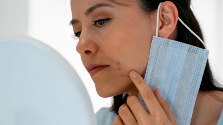 Maskné woman checking acne under her mask