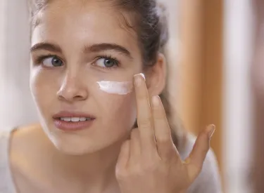 Teenage girl applying moisturizer